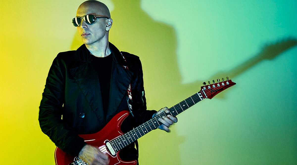 Joe Satriani tocando uma guitarra Ibanez vermelha