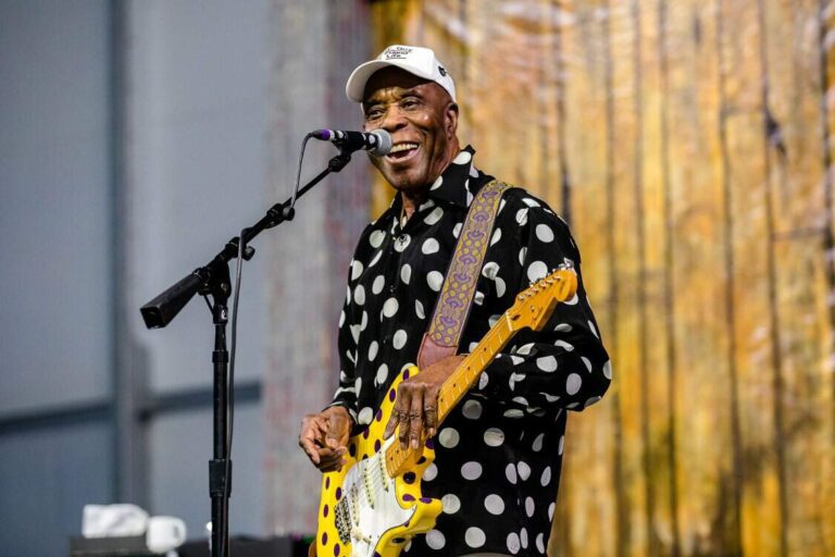 Buddy Guy se apresentando no New Orleans Jazz & Heritage Festival, em 2018. Sorrindo e com de praxe, com sua camisa e guitarra stratocaster de bolinhas