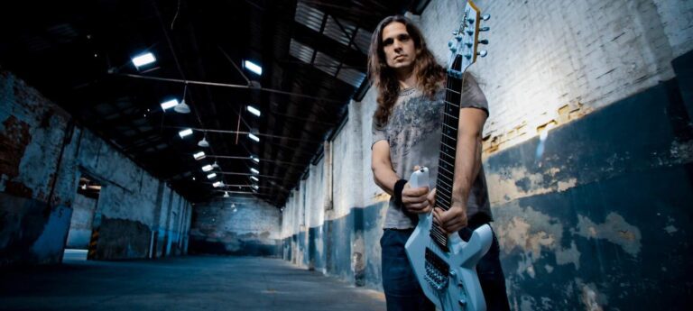 Kiko Loureiro posando para foto em um galpão.