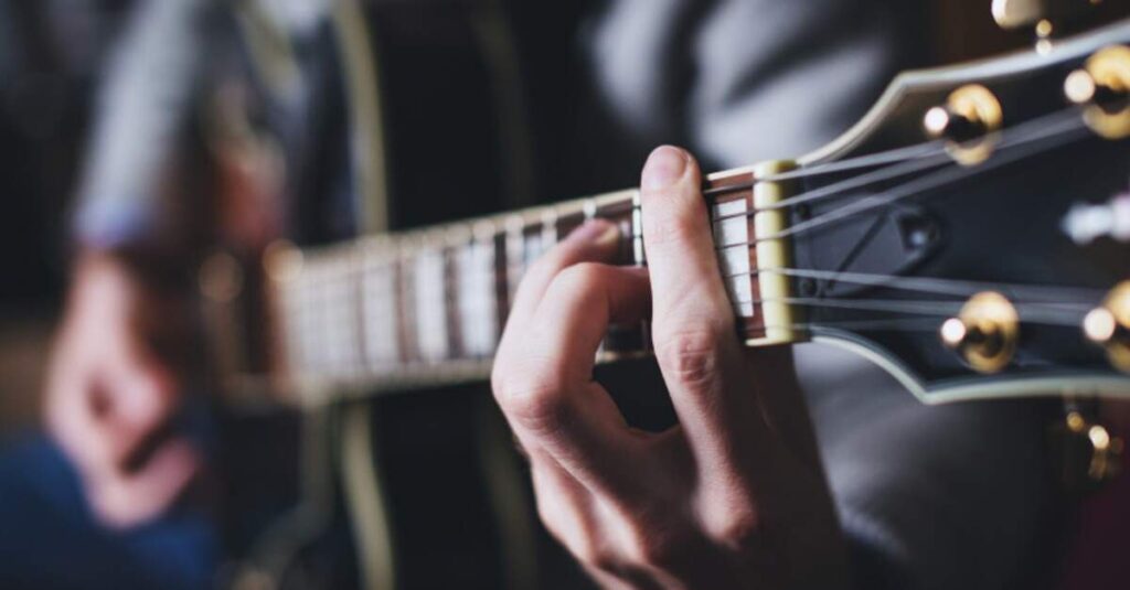 Guitarrista fazendo um acorde