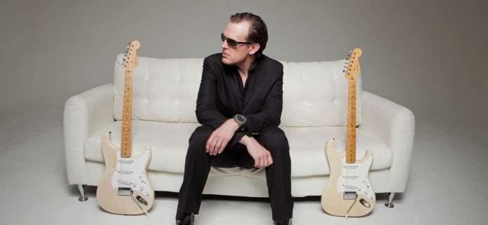 joe-bonamassa Joe Bonamassa sentado no sofá com duas guitarras Fender Stratocaster