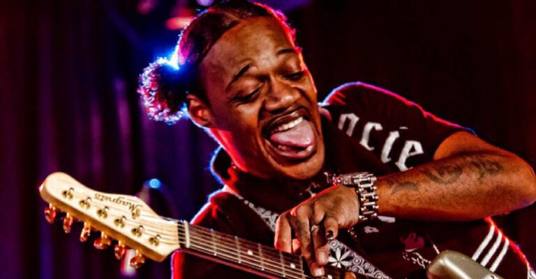 Eric Gales fazendo careta ao tocar guitarra