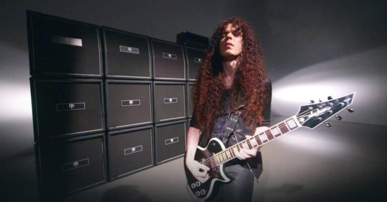 Marty Friedman à frente de uma parede de caixas