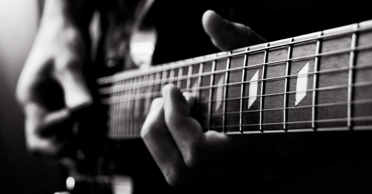 Foto em preto e branco de um músico tocando guitarra