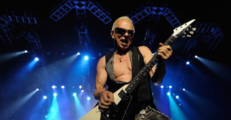 Rudolf Schenker tocando guitarra em um palco iluminado