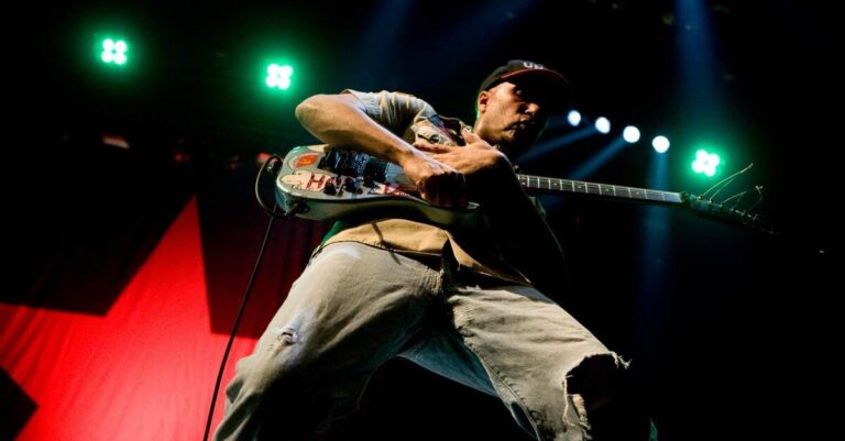 Tom Morello tocando em um palco iluminado