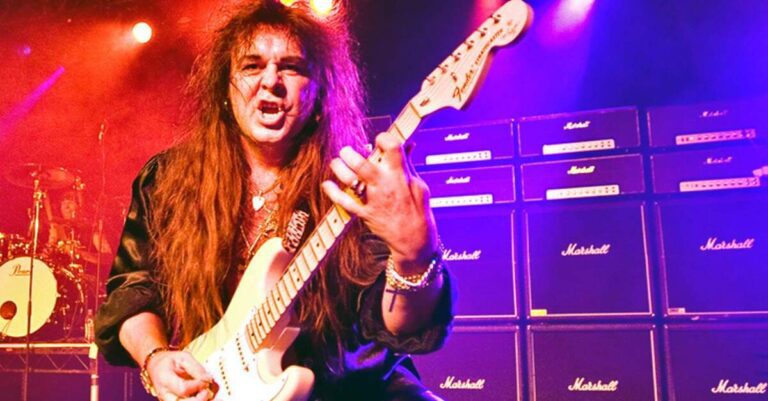 Malmsteen tocando guitarra à frente de uma parede de Marshalls