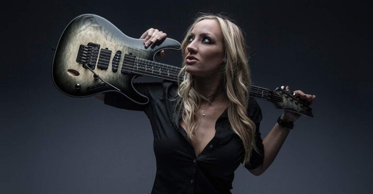 Nita Strauss segurando uma guitarra Ibanez sobre os ombros