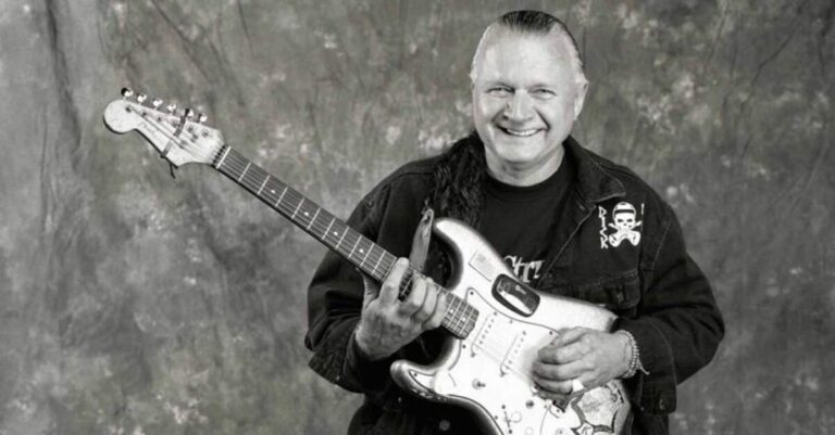 Dick Dale segurando uma guitarra e sorrindo