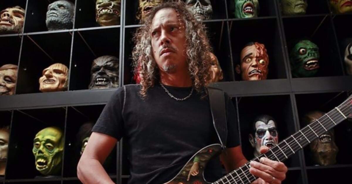 Kirk Hammett tocando guitarra com bonecos de terror ao fundo