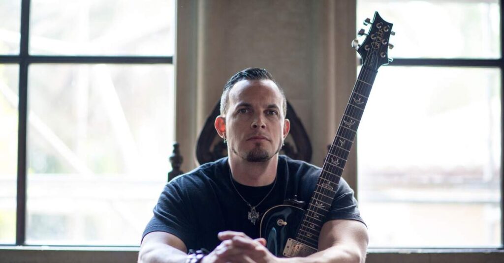 Mark Tremonti sentado com uma guitarra PRS