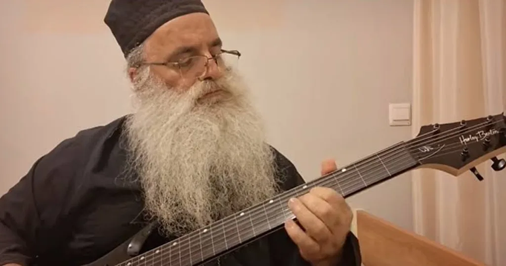Padre ortodoxo grego viraliza ao transformar hinos religiosos em metal com guitarra de oito cordas sem trastes Padre grego viraliza ao criar metal com hinos religiosos usando guitarra Harley Benton de oito cordas sem trastes.